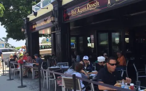 A group of people sitting at tables outside of an establishment.