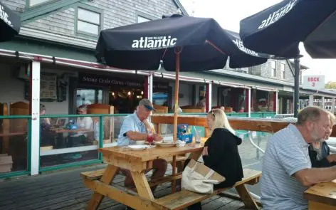 A man and woman sitting at an outdoor table under an umbrella.