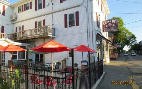 A restaurant with red umbrellas and chairs outside.