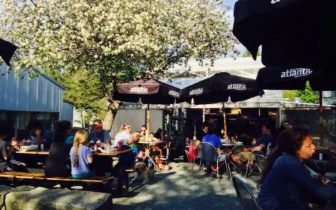 A group of people sitting at tables under umbrellas.