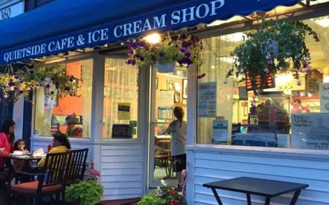 A woman standing outside of a cafe and ice cream shop.