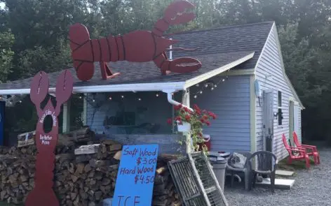 A lobster sign sitting on top of a pile of wood.