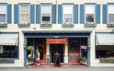 A small store front with people walking on the sidewalk.