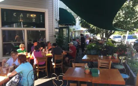 A group of people sitting at tables outside.