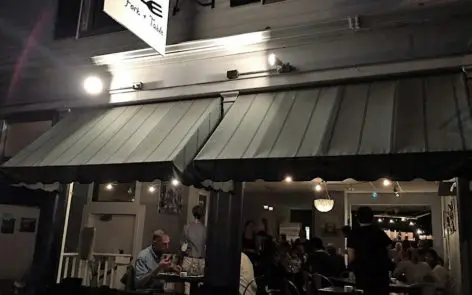 A group of people sitting at tables outside of a restaurant.