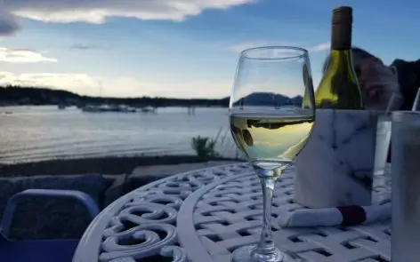 A glass of wine on the table near the water.