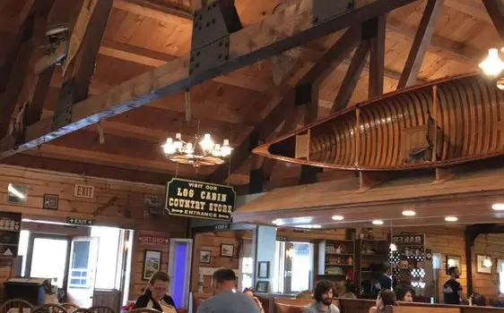 A restaurant with people sitting at tables and some of the tables are made from wood.