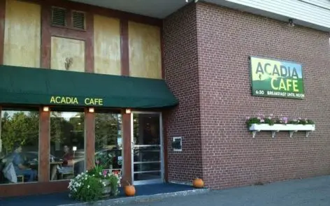 A restaurant with green awnings and pumpkins outside.