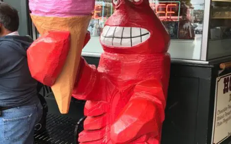 A red fire hydrant with an ice cream cone on top of it.