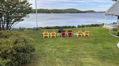 Colorful chairs arranged facing an serene lake with trees in the background.